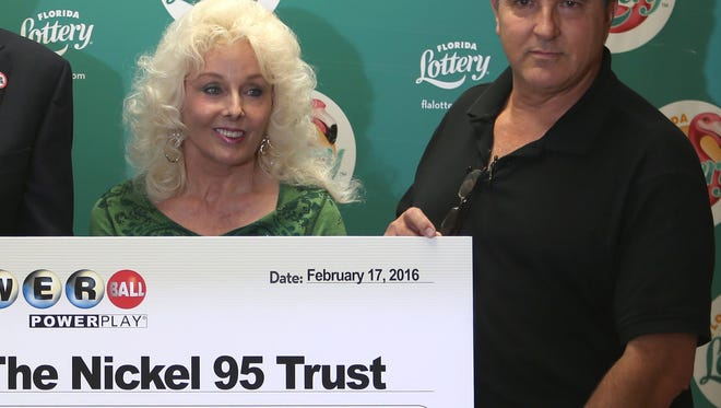 Florida Lottery Secretary Tom Delacenserie, left, presents Maureen Smith and David Kaltschmidt with their one-third share of the Jan. 13, 2016, world record Powerball jackpot.