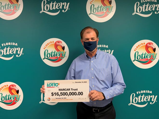 Indialantic lottery lawyer聽Kurt Panouses holds a $16.5 million check won by an undisclosed Martin County resident at the Florida Lottery offices in Tallahassee.